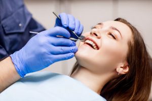 The dentist performs dental cleaning on the young woman.